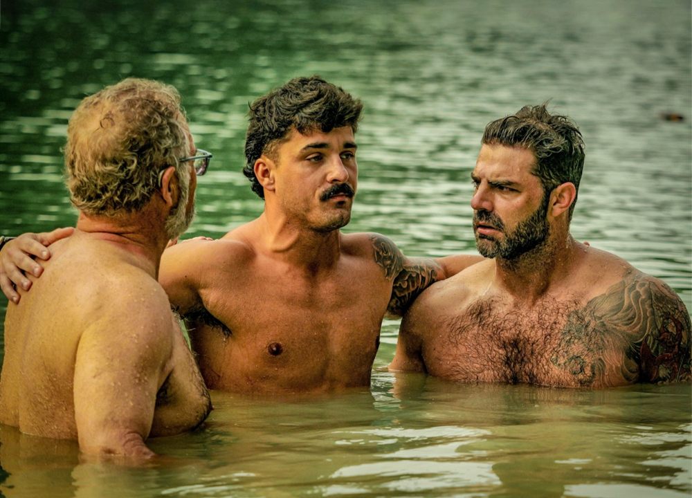 Hunter standing in the water with two men moments before his baptism at Mighty Men Camp