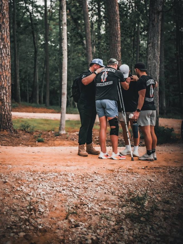 Men praying together in the woods at Mighty Men Camp